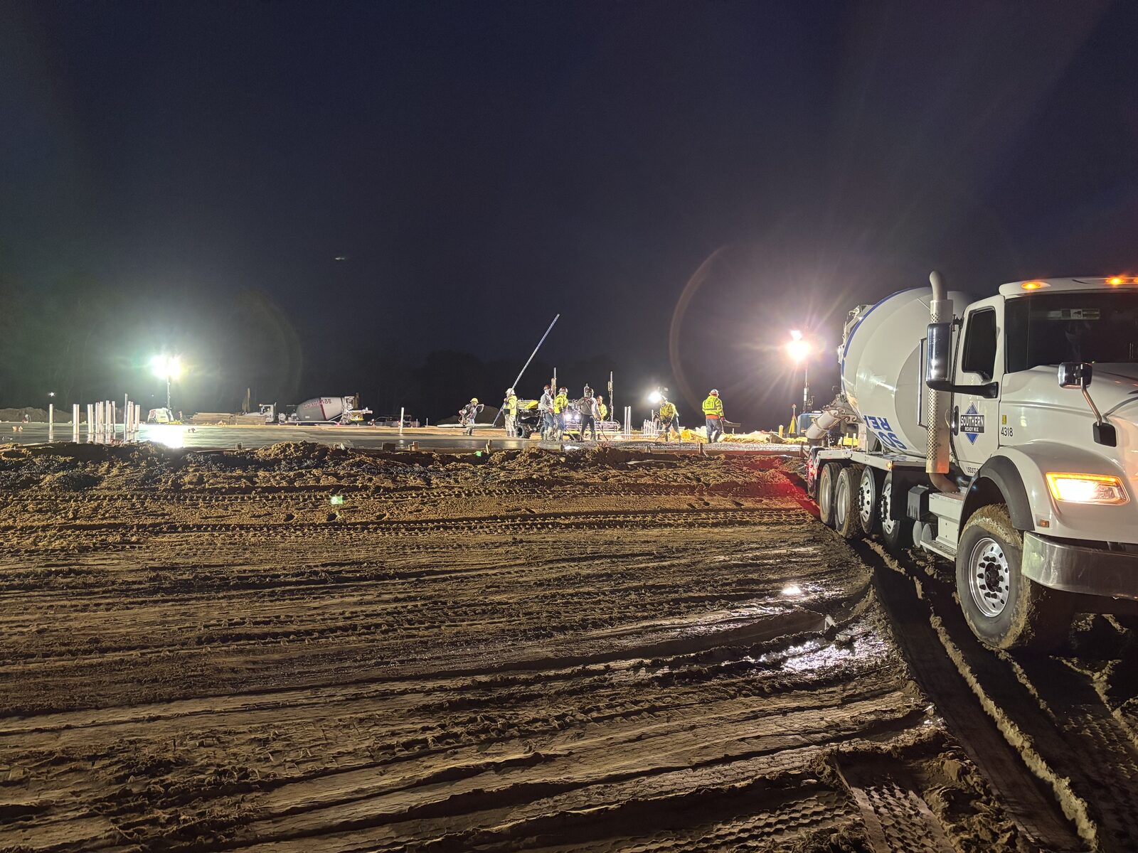 Night pour with SRM mixer trucks and crew working under lights on commercial project