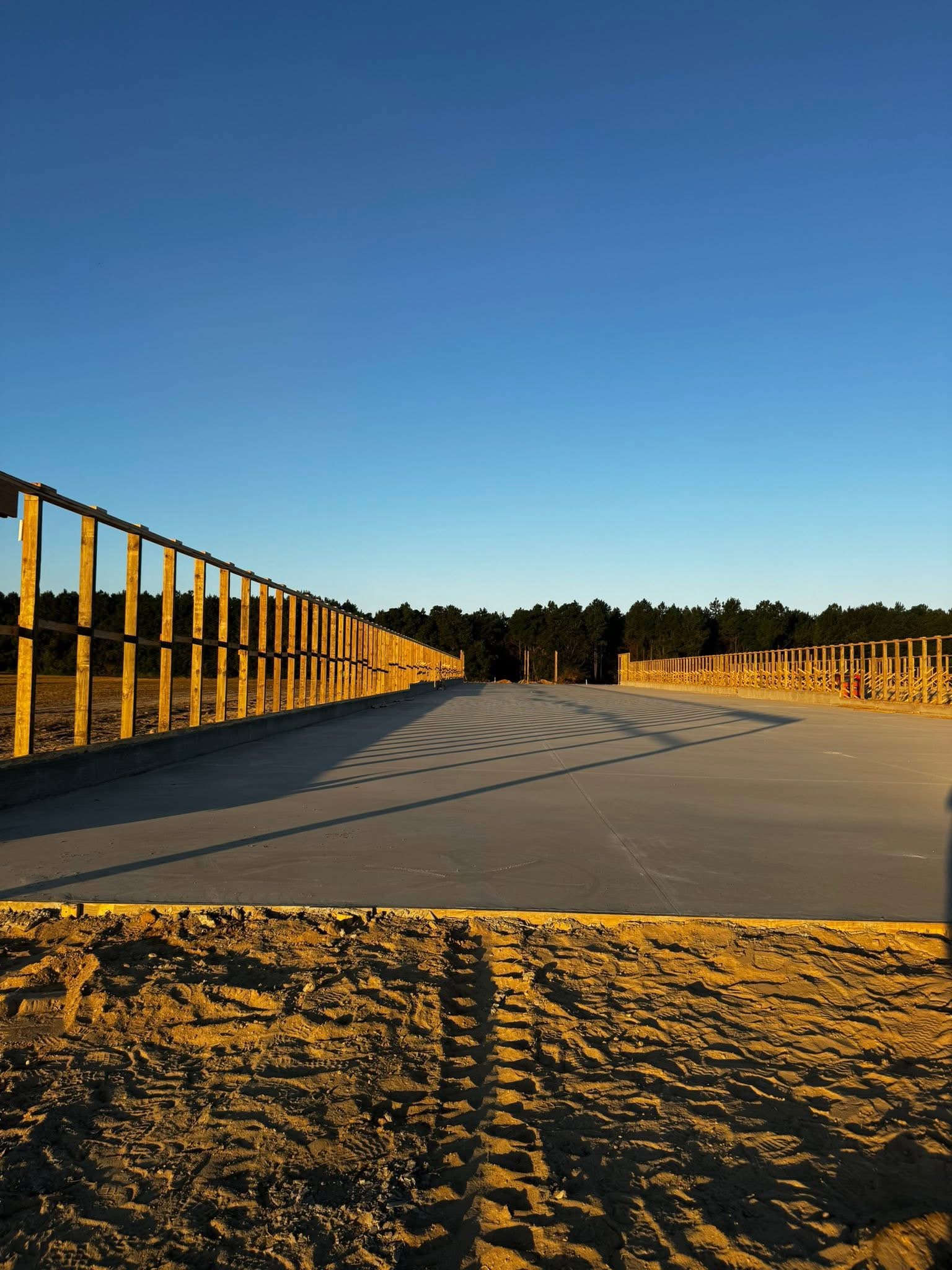 Golden hour concrete slab pour with wood forms and blue sky